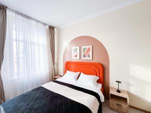 une chambre avec un grand lit et une tête de lit orange dans l'établissement Bekarys Hotel, à Astana