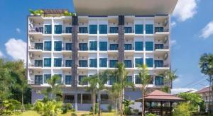 a large white building with palm trees in front of it at Sixty-Sixplace in Ban Khok Lo