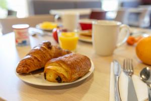 un tavolo con un piatto di croissant e succo d'arancia di Ace Hotel Brive a Brive-la-Gaillarde