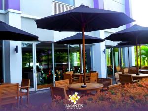 een patio met tafels en stoelen met parasols bij Amantis Hotel in Demak