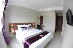 een hotelkamer met een groot bed en een tv bij Amantis Hotel in Demak