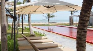 eine Gruppe von Stühlen unter einem Sonnenschirm neben einem Pool in der Unterkunft Red Z The Ocean in Ban Tanot Noi