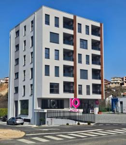 a white building with a pink sign in front of it at Apartman Pinjuh in Široki Brijeg