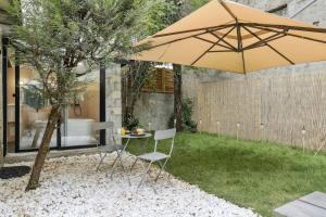 un patio avec un parasol, une table et des chaises dans l'établissement Maisons Alfort 6 Luxurious little house with private garden and Jacuzzi, à Maisons-Alfort