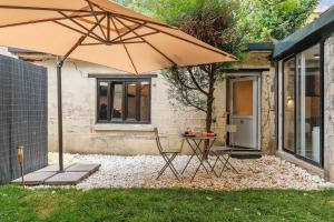 un patio avec une table et un parasol dans l'établissement Maisons Alfort 6 Luxurious little house with private garden and Jacuzzi, à Maisons-Alfort