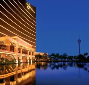 a building with a reflection in the water at night at Wynn Macau Hotel in Macau