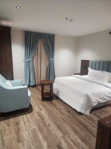 une chambre avec un grand lit et une chaise bleue dans l'établissement Makarim Palm Hotel, à Rabigh