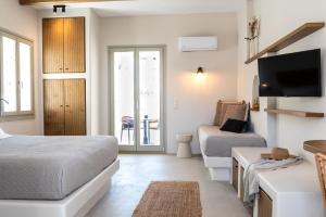 a bedroom with a bed and a couch and a tv at Althea Anafi Suites in Anafi