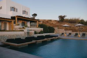 a swimming pool next to a villa with chairs at Evi Suites & Villas in Mikonos