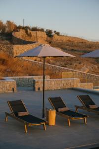 three lounge chairs and an umbrella next to a pool at Evi Suites & Villas in Mikonos +68 photos