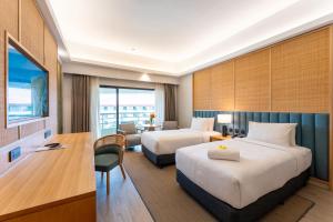 a hotel room with two beds and a desk at Swiss-Grand Beach Resort Kuantan - Newly Upgraded 5-Star in Kuantan