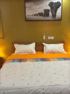 アビジャンにあるAKAWABA Residenceの寝室にある白いシーツと枕が置かれたベッド