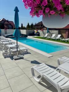 eine Reihe von Liegestühlen und einem Sonnenschirm neben einem Pool in der Unterkunft Apartament Aqua Mazury z jacuzzi in Lyck