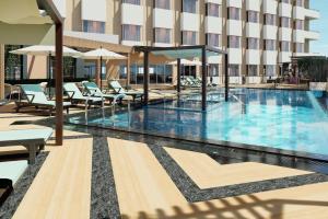 a swimming pool with chairs and umbrellas in a hotel at Vivanta Gurugram Sector 95A in Gurgaon