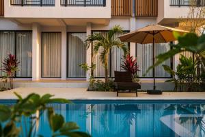 een parasol en een stoel naast een zwembad bij Sinapa Suites in Ko Pha Ngan
