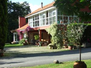 una casa con muchas flores delante de ella en Bungalow Camping Los Manzanos, en Santa Cruz de Oleiros