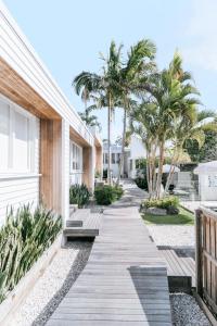 ein Fußweg zwischen zwei Gebäuden mit Palmen in der Unterkunft Bask & Stow I Luxe Guesthouse in Byron Bay