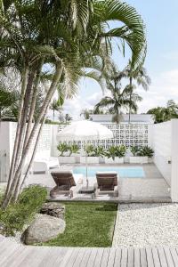ein Resort mit Pool, zwei Liegestühlen und Palmen in der Unterkunft Bask & Stow I Luxe Guesthouse in Byron Bay