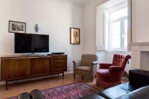uma sala de estar com uma televisão de ecrã plano e 2 cadeiras em Lisbon Secret & River View Family Flat em Lisboa