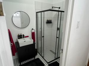 a bathroom with a shower with a sink and a mirror at Layover on Loerie in Cape Town +7 photos