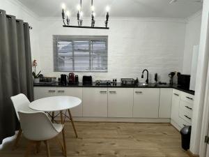 a kitchen with white cabinets and a white table at Layover on Loerie in Cape Town