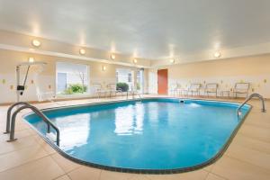 una piscina en una habitación de hotel con sillas y mesas en Amerivu Inn and Suites, en Grand Forks