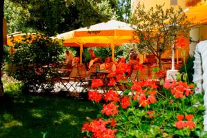 a group of people sitting at a table with red flowers at Seibel's Park Hotel in Munich