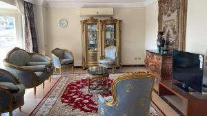 a living room with chairs and a tv and a table at فيلا كامله للايجار in Kafr Ghaţāţī