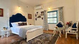 een slaapkamer met een blauw bed en een raam bij Seclude Hampi 1800 in Jāmb