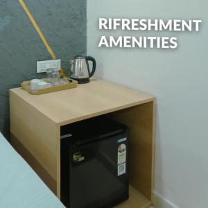 a small refrigerator under a desk with a sign that reads retirement amenities at Hotel Ansh Har Regency in Vidisha