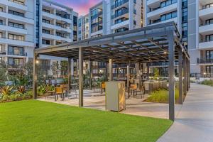 a pavilion with tables and chairs in front of a building at Modern 2BR Free parking near Olympic park in Sydney