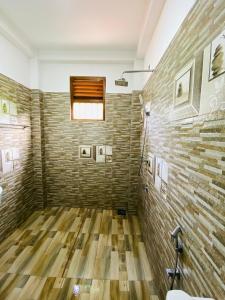 een badkamer met een bakstenen muur en houten vloeren bij Villa Chingu in Kamburugamuwa
