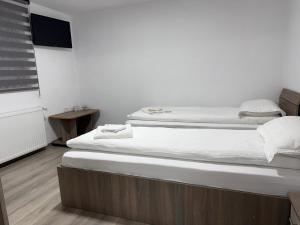 two beds in a room with white walls at Casa Lupilor 2 Vidraru in Căpăţîneni-Ungureni