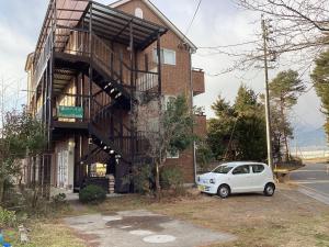 una macchina bianca parcheggiata di fronte a un edificio di 森のハイジ ad Azumino