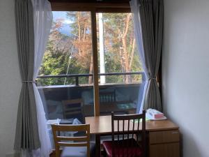 een tafel en stoelen in een kamer met een groot raam bij 森のハイジ in Azumino