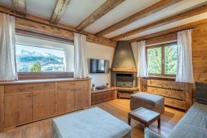 a living room with a large window and a fireplace at Chalet Capriol by My Villa Collection in Cortina dʼAmpezzo