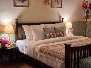 een slaapkamer met een bed met 2 lampen en bloemen bij Seclude Hampi 1800 in Jāmb
