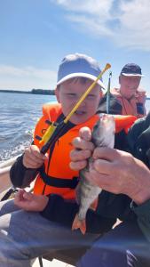 een jonge jongen met een vis in een boot bij Pohja in Joensuu