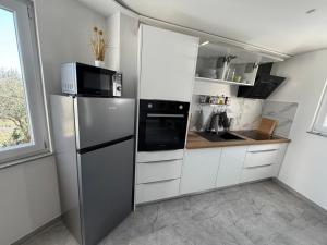 a kitchen with white cabinets and a stainless steel refrigerator at Green view apartment in Koper +5 photos