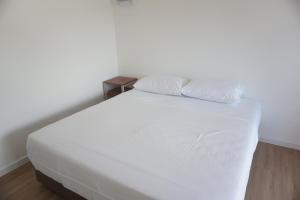 a white bed with two pillows on top of it at Travellers Palm in Koh Phangan