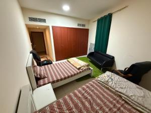 ein Schlafzimmer mit zwei Betten und einem Stuhl und einer Tür in der Unterkunft Ajman Rashdiya 1 in Ajman  + 5 Fotos