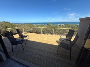 three chairs on a deck with the ocean in the background at Seenekal views in Cannon Rocks