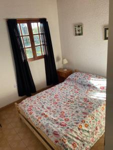 a bedroom with a bed with a floral comforter and a window at Teresita6 in Santa Teresita