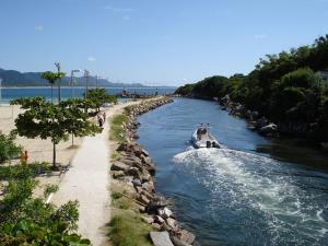 un barco que viaja por un río junto a una playa en FLORIPA FLORINDO APART, en Florianópolis