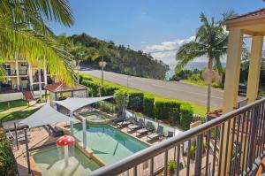 uma varanda com piscina e palmeiras em South Pacific Apartments em Port Macquarie
