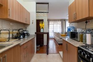 a kitchen with wooden cabinets and a living room at Royal Homes in Nairobi