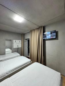 een slaapkamer met twee bedden en een tv aan de muur bij ИксаОтель in Simkent