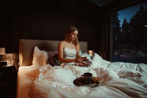 a woman sitting on a bed with a cup at Aurora Igloo Village Ylläs - Hot Tub in Ylläsjärvi