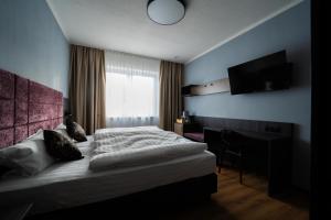 a bedroom with a bed and a desk and a television at PEN Smart Hotel in Türkheim +12 photos