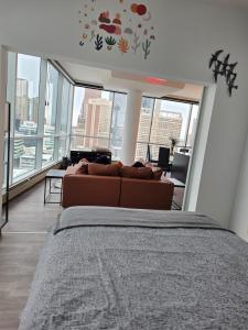 a bedroom with a bed and a couch in a room with windows at Breath-Taking-View-5 Guest DTskyline 18th Floor in Calgary